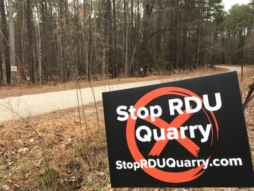 RDU officials side with mining interests in clash over Umstead quarry a sign alongside a road reads "Stop RDU Quarry"
