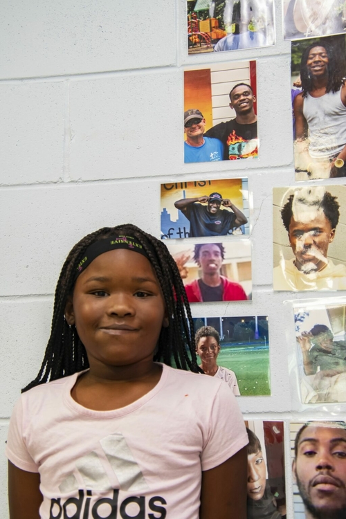 First floods, now fires: How neglect and fraud hobbled Prichard A young girl in a pink shirt stands in front of photos plasters on a wall.