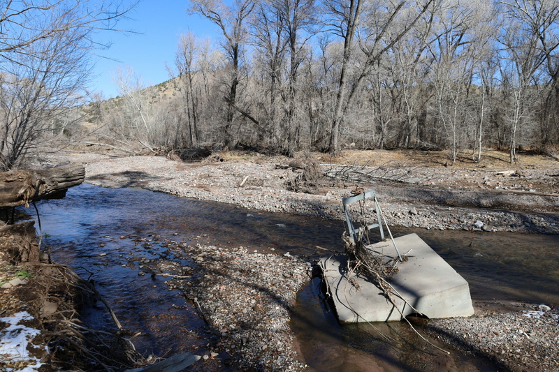 Disaster recovery efforts boost initiative to map acequias in the state The Mimbres river flows between land with trees on either side of it. In the middle of the river sits a tilted headgate with debris on it, broken and slumping into the water.